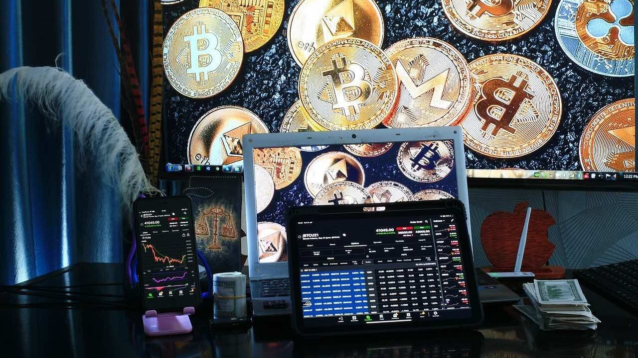 A computer device showing crypto trading with different cryptocurrencies in the background of the picture.