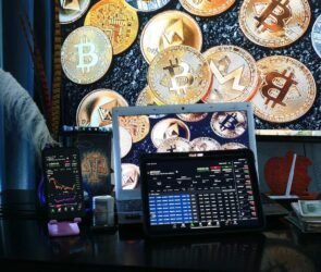 A computer device showing crypto trading with different cryptocurrencies in the background of the picture.