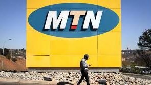 A banner of MTN and a man walking past it.