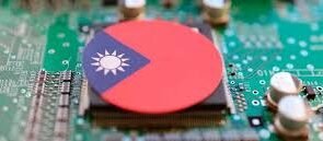 A close-up of a green semiconductor circuit board with a chip covered by a circular sticker featuring the flag of Taiwan.