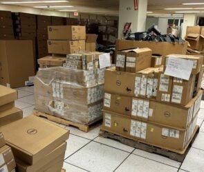 Pallets of laptops and other IT devices in an ITS storage facility, many never opened or lightly used, scheduled for destruction.