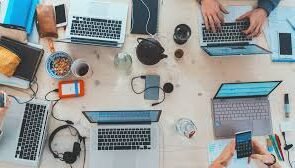 A picture containing many personal computer on the desk.