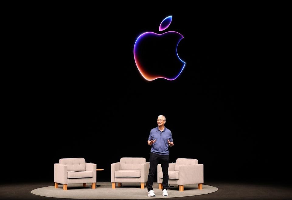 An image of a man on a stage with Apple symbol behind him.